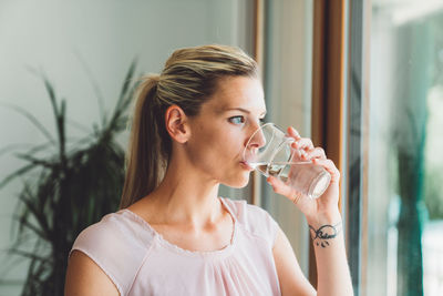 Young woman drinking water at home