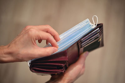 Cropped image of woman removing mask from wallet