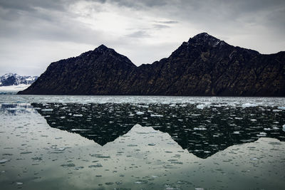 Scenic view of sea by mountains against sky