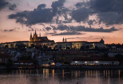 River amidst buildings against sky during sunset