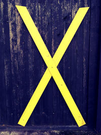 Full frame shot of yellow arrow sign on wooden wall
