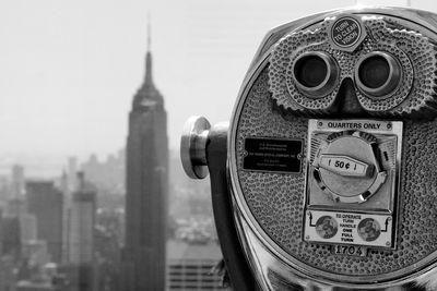 Close-up of coin-operated binoculars against buildings in city