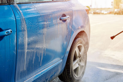 Cleaning car with high pressure water at car wash station