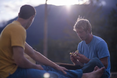 Two men eating crepes at sunset on roof in outdoors squamish canada