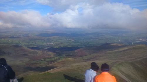 Low section of people on mountain against sky