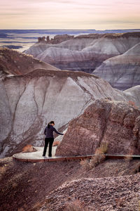 Woman standing on footpath against rock formation