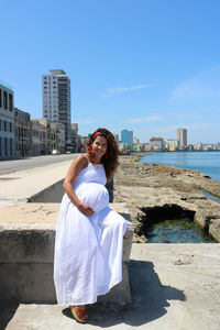 Young woman standing by sea against sky