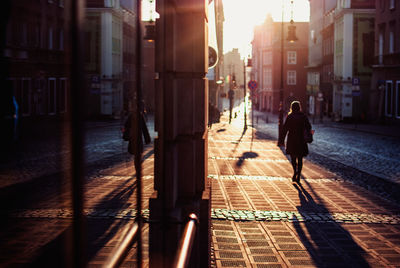 Rear view of man walking on street amidst buildings