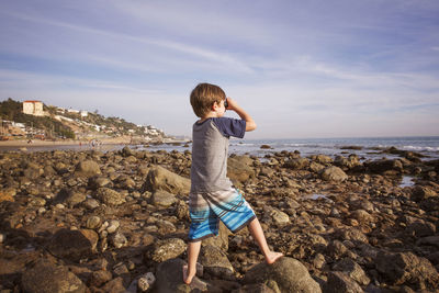 Boy looking through binoculars at beach