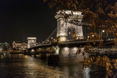 Illuminated bridge over river at night