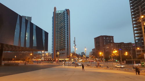 Modern buildings in city against sky at dusk