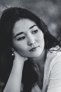 Close-up of young woman looking away sitting outdoors