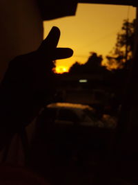 Silhouette person hand against sky during sunset