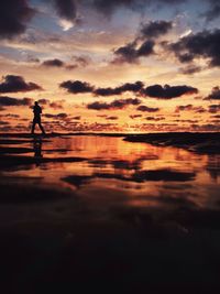 Silhouette of people on beach at sunset