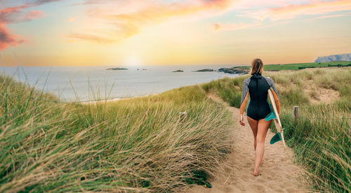 Full length of woman standing on beach against sky during sunset