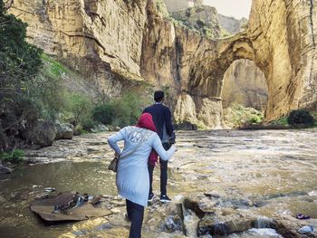 Rear view of man standing on rock by river