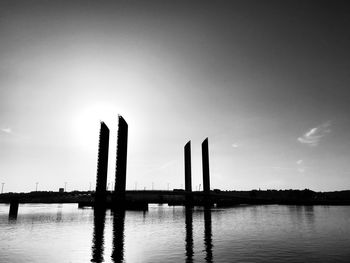 Silhouette bridge over river against sky during sunset