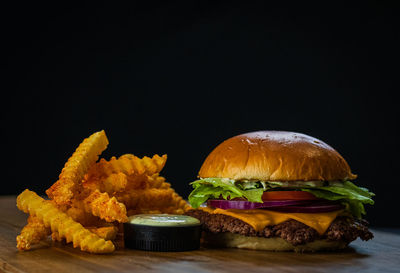 Close-up of burger on table against black background