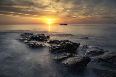 Beautiful sunset on the coast with the waves passing over the rocks