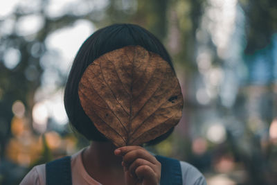 Close-up of woman holding autumn leaf