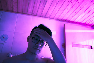 Portrait of young man against illuminated ceiling