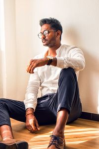 Full length of young man sitting against wall