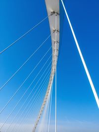 Low angle view of suspension bridge against blue sky