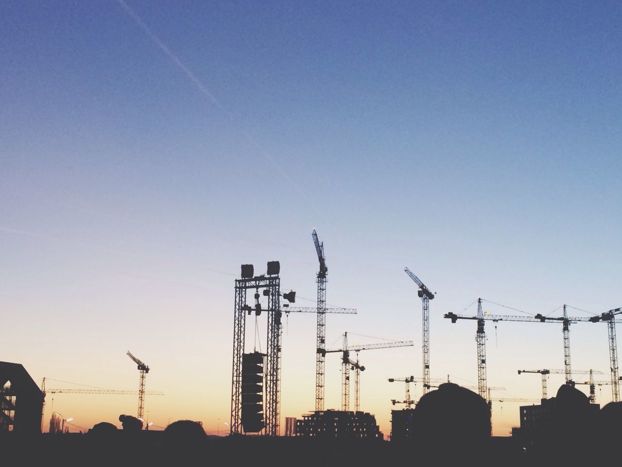 building exterior, clear sky, built structure, architecture, construction site, low angle view, development, silhouette, crane - construction machinery, crane, copy space, construction, industry, blue, sunset, city, incomplete, fuel and power generation, technology, electricity pylon