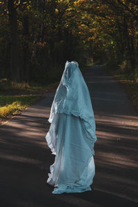 Rear view of woman on road amidst trees in forest