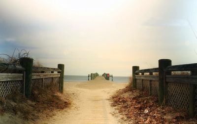 Pier on beach against sky during sunset