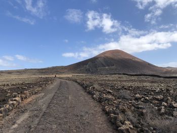 Dirt road amidst desert against sky