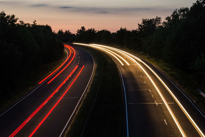 Light trails on road against sky at night