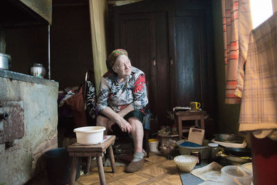 Senior woman sitting amidst utensils at home