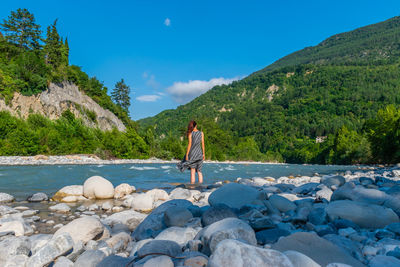 Rear view of man standing on rock against sky