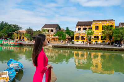 Buildings by lake against sky