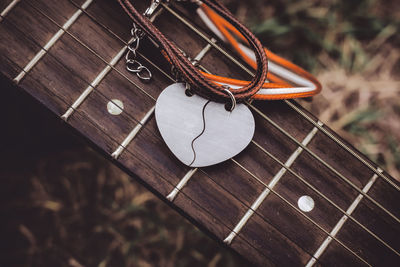 High angle view of heart shape with bracelet over guitar