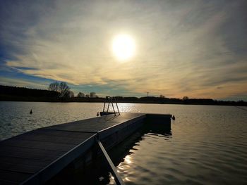 Pier on lake against sky during sunset