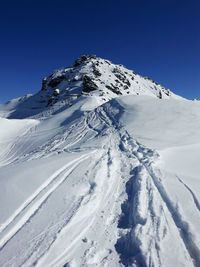 Scenic view of snow covered mountain against clear blue sky