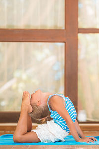 Side view of woman lying on window