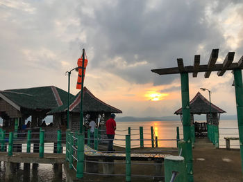 Lifeguard hut on beach by sea against sky during sunset