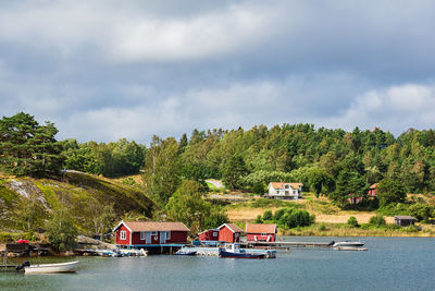 Scenic view of river by trees and houses against sky