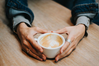 Midsection of man holding coffee cup on table