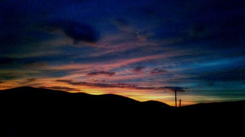 Silhouette landscape against dramatic sky during sunset