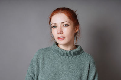 Portrait of young woman standing against wall