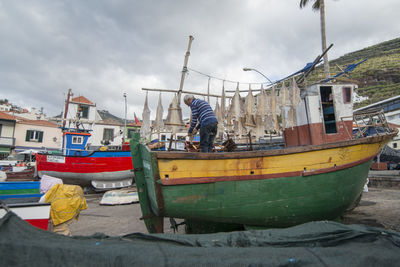 Boats moored at harbor against sky