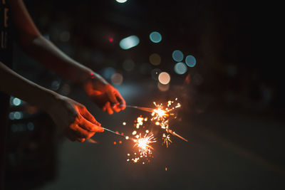 Cropped hand holding sparklers at night