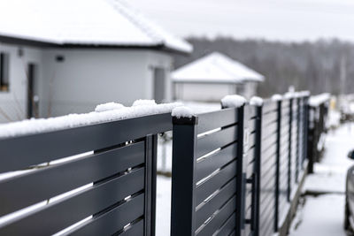 Modern anthracite panel fence with falling snow, visible sliding gate.