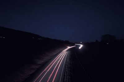 Light trails on road against sky at night