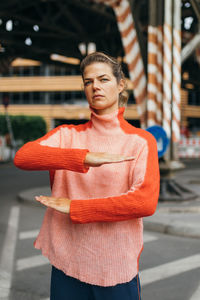 Portrait of woman gesturing equal sign while standing on road