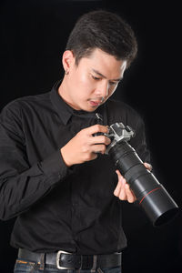 Man using camera against black background